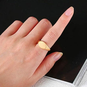 Stainless steel classic oval signet pinky ring on hand, sleek satin finish.