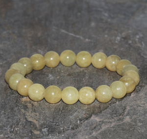 Natural yellow beryl gemstone bead bracelet on stone surface.