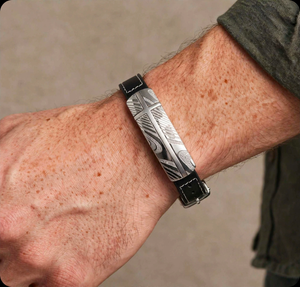 Damascus steel and black leather bracelet from T.M.J featuring a sleek, handcrafted design with metal accents and adjustable leather strap.