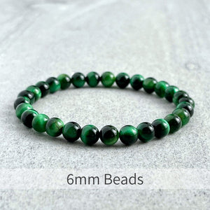 Green Tiger Eye Bead Bracelet with 6mm Beads on a Stone Surface.