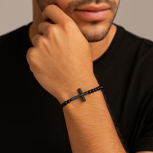 Gold macrame bead bracelet with a CZ diamond cross charm by T.M.J, showcasing intricate knot details and elegant design.