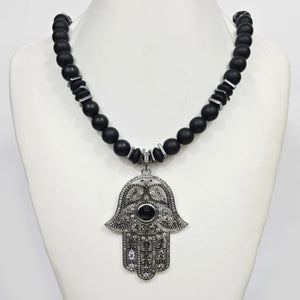 Large silver Hand of Hemsa pendant on T.M.J beaded necklace with Austrian crystals and matte onyx beads, elegant jewelry piece.
