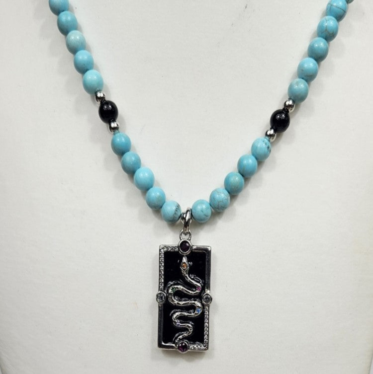 Silver enamel snake dog tag pendant on a turquoise beaded necklace, stylish T.M.J jewelry accessory.