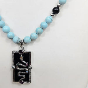 Silver enamel snake dog tag pendant on a turquoise beaded necklace, stylish jewelry by T.M.J with detailed design.