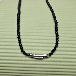 Black onyx beaded necklace with silver and gold honey bee pendant, featuring intricate detailing and a polished finish.
