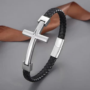 Flat braided leather bracelet with a large cross pendant by T.M.J, featuring gold accents and detailed craftsmanship.
