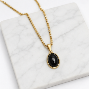 Gold-plated steel pendant with black agate cabochon, featuring T.M.J’s Halcyon pendant design.