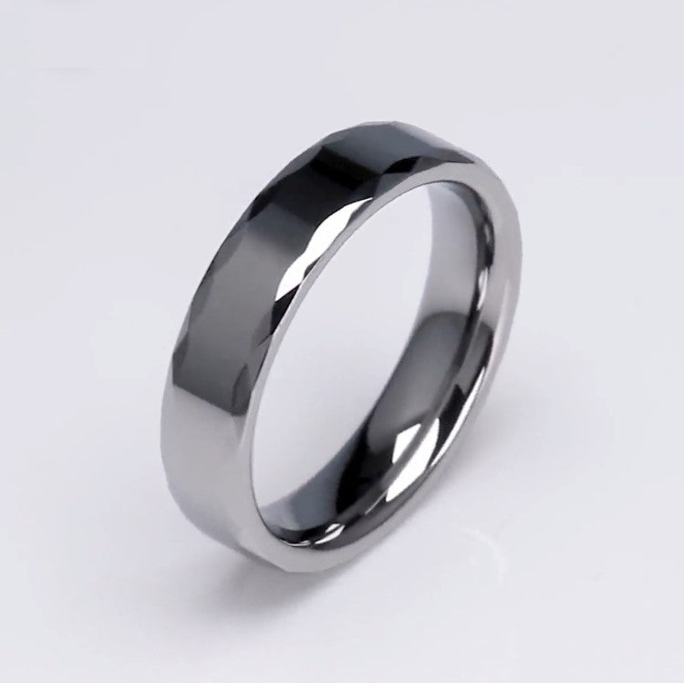Silver tungsten carbide ring called The Rumba by T.M.J, featuring a sleek, polished band with subtle engraving details.