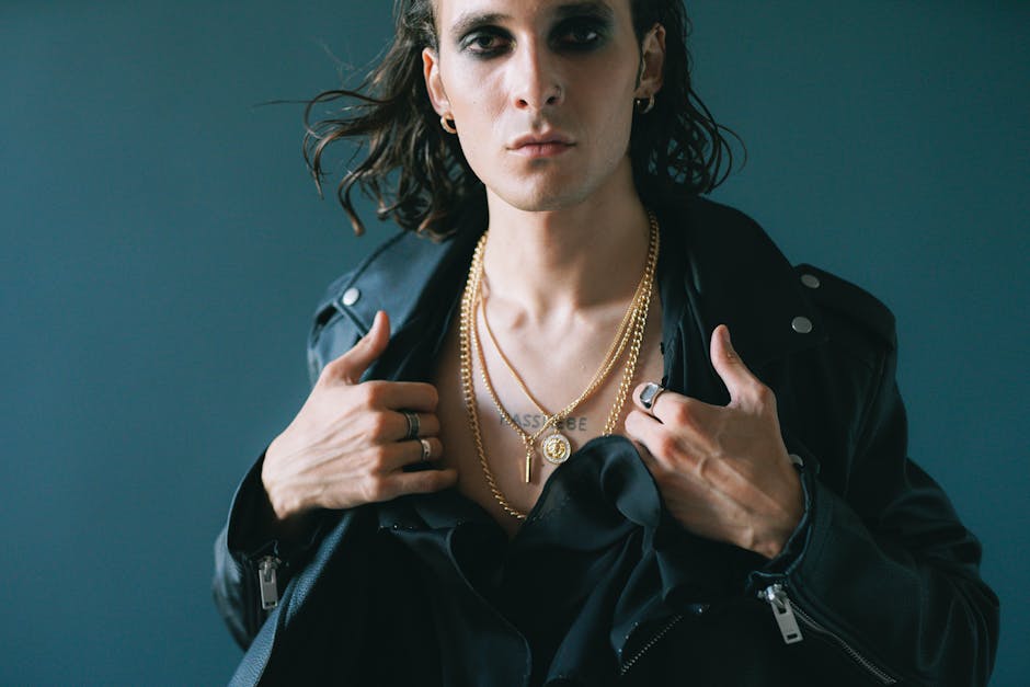 Man wearing a silver pendant necklace over a dark shirt