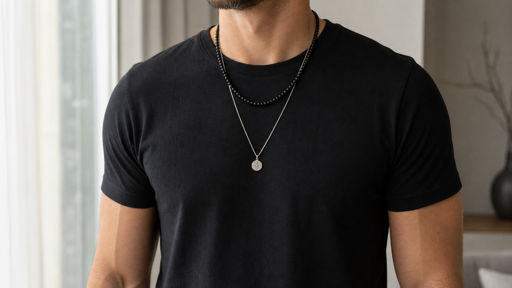 Man wearing layered black bead and silver pendant necklaces