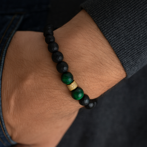 Black faceted agate and green tiger eye beaded bracelet with gold pavé spacer, worn on wrist.