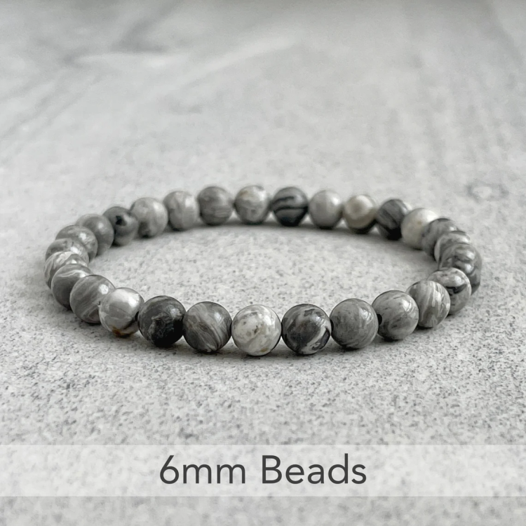 Natural gray jasper beads bracelet with 6mm stones arranged in a circle on a marble surface.