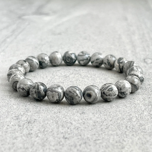 Natural Gray Jasper beads bracelet on a textured surface.