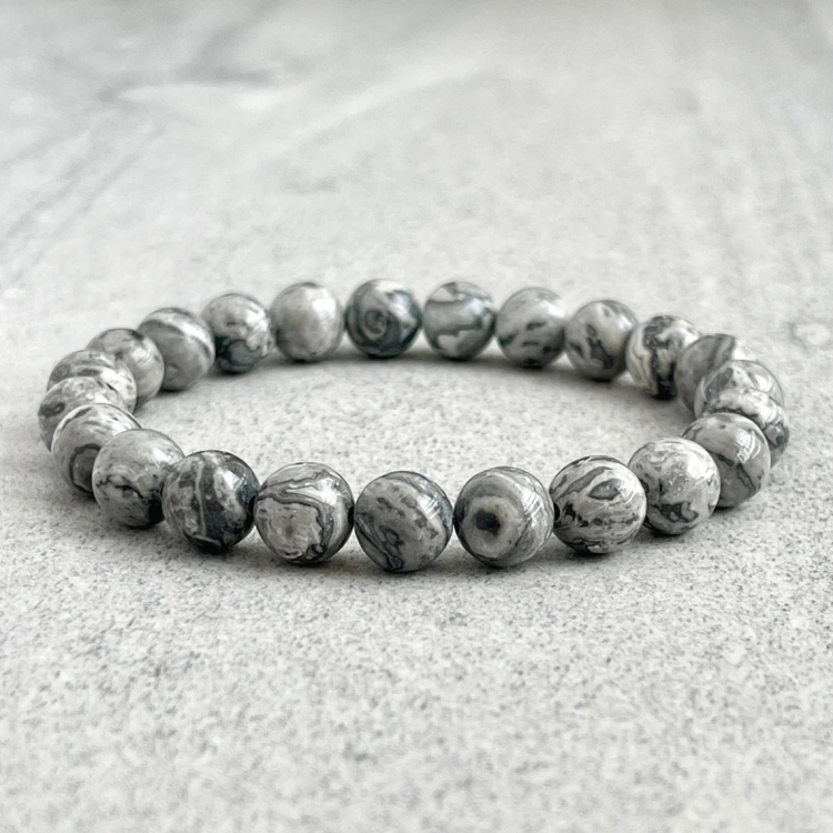 Natural Gray Jasper beads bracelet on a textured surface.
