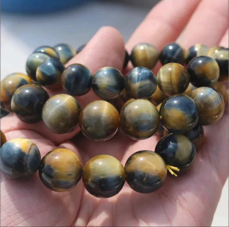 Natural Gold Blue Tiger Eye Bead Bracelet in hand, showcasing glossy 14mm beads with golden and deep blue hues, handcrafted for confidence and clarity.