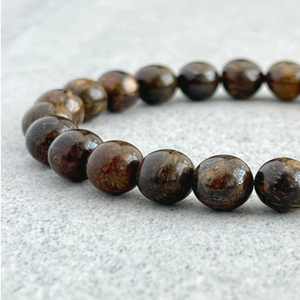 Natural bronzite stone beads bracelet on a light surface.