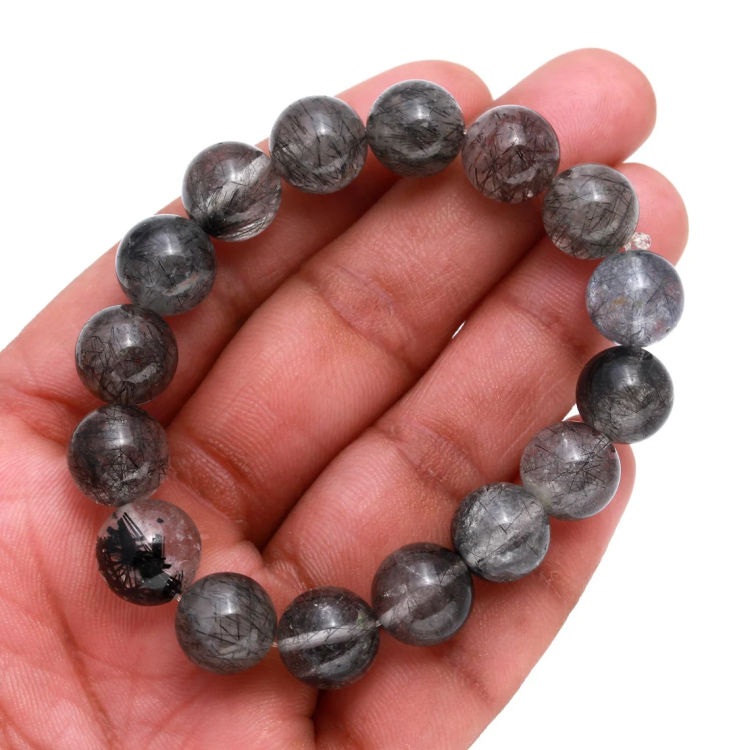 Black Rutilated Quartz beaded bracelet for spiritual growth, held in hand.