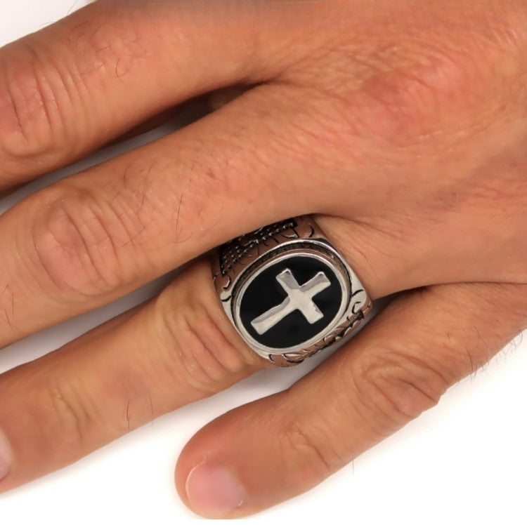 Men’s vintage oval cross signet ring with black enamel base on hand.
