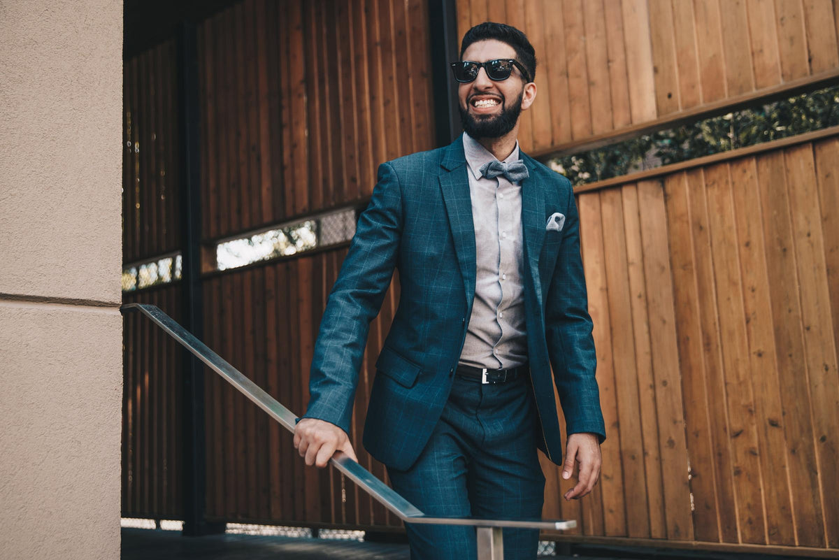 Smiling man in a blue check suit and bow tie walking down outdoor steps