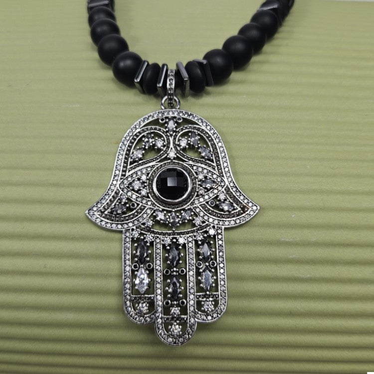 Large silver Hand of Hemsa beaded necklace by T.M.J with Austrian crystals and matte onyx beads, featuring a striking pendant.