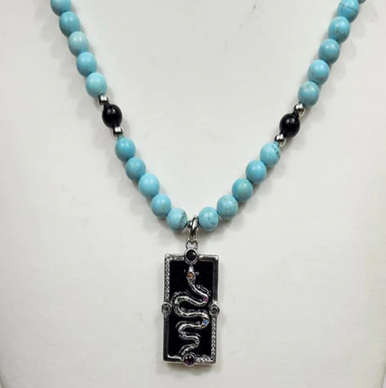 Silver enamel snake dog tag pendant from T.M.J on a vibrant turquoise beaded necklace.