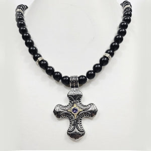 Stainless steel cross pendant on black turmaline beaded necklace by T.M.J, close-up of the religious jewelry with beaded design.