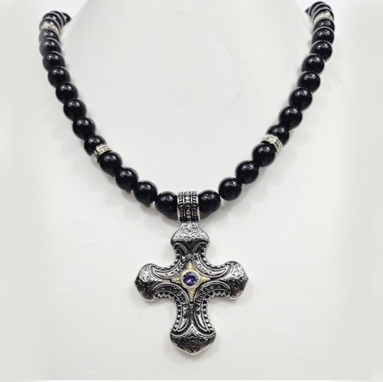 Stainless steel cross pendant on black turmaline beaded necklace by T.M.J, close-up of the religious jewelry with beaded design.