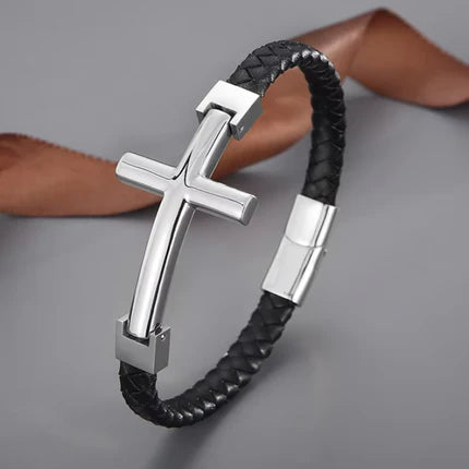 Flat braided leather bracelet with a large cross pendant by T.M.J, featuring gold accents and detailed craftsmanship.