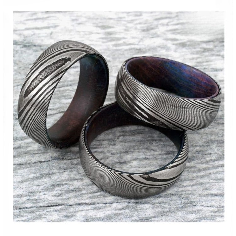 Men’s Damascus Steel Titanium Ring by T.M.J with purple hard wood inner sleeve, 8mm wide, showcasing intricate steel pattern and wood inlay.