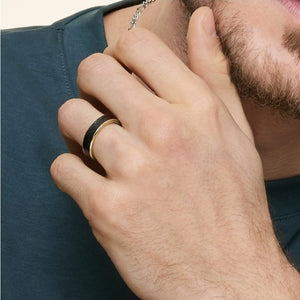 Black tungsten carbide ring with gold accent, 6mm width, by T.M.J, featuring a sleek, polished design suitable for men's jewelry.