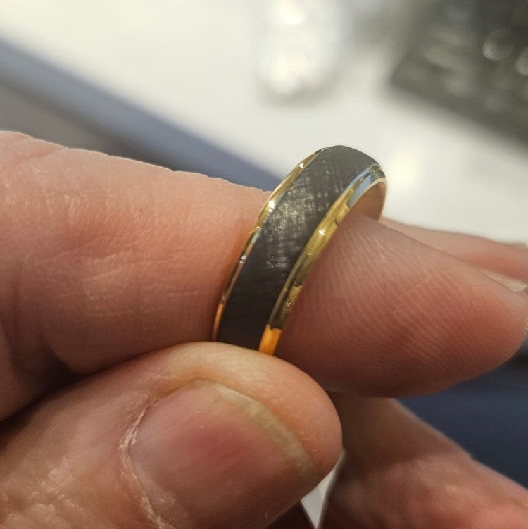 Black tungsten carbide ring with gold accent, 6mm width, from T.M.J, showcasing sleek design and polished finish.